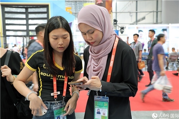 東博會現(xiàn)場，馬來西亞展商在同中方工作人員交談。人民網(wǎng)記者 趙益普攝