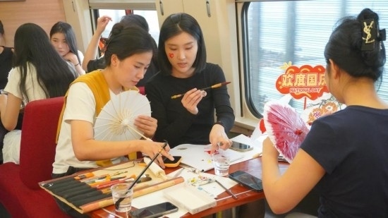 10月1日，旅客們在G1634次列車上給油紙傘作畫。新華社記者周義 攝