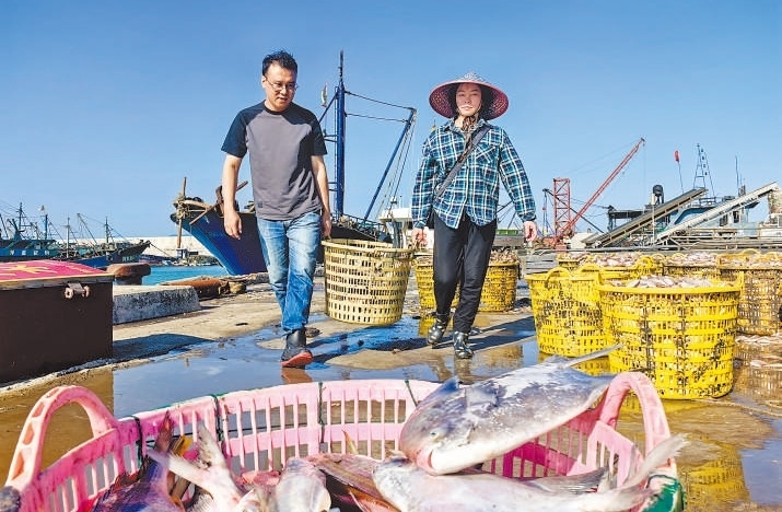 許小斌（左）和漁民一起搬運海鮮。本報記者 付 文攝