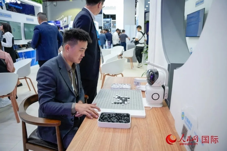 觀眾在中國移動(dòng)國際有限公司展臺體驗(yàn)智慧圍棋機(jī)器人。人民網(wǎng) 塔里克·易卜拉欣攝
