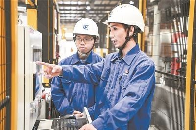 在廣西柳工機(jī)械股份有限公司生產(chǎn)車(chē)間內(nèi)，一名高級(jí)技師（右）給徒弟講解數(shù)控設(shè)備操作細(xì)節(jié)。新華社記者 曹祎銘攝