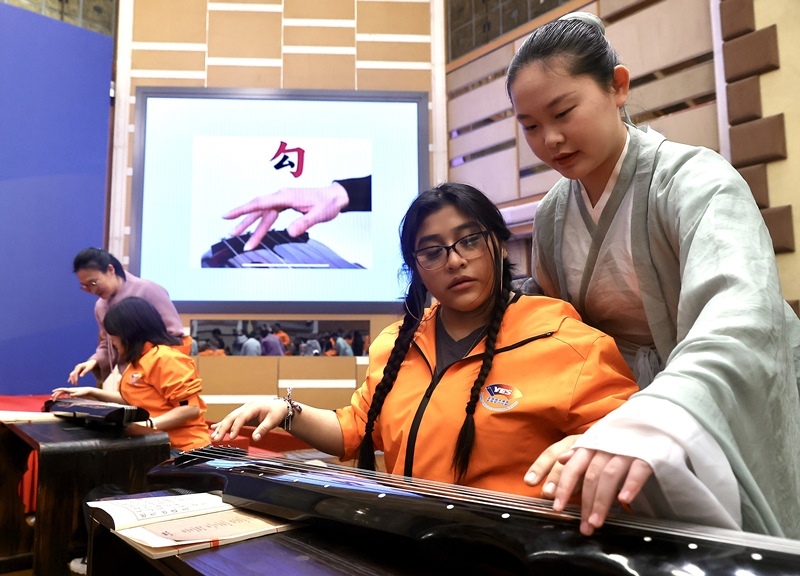 2024年3月20日，美國華盛頓州中學生代表團北京大學交流活動在北京大學英杰交流中心舉行。圖為來自華盛頓州的中學生體驗古琴。