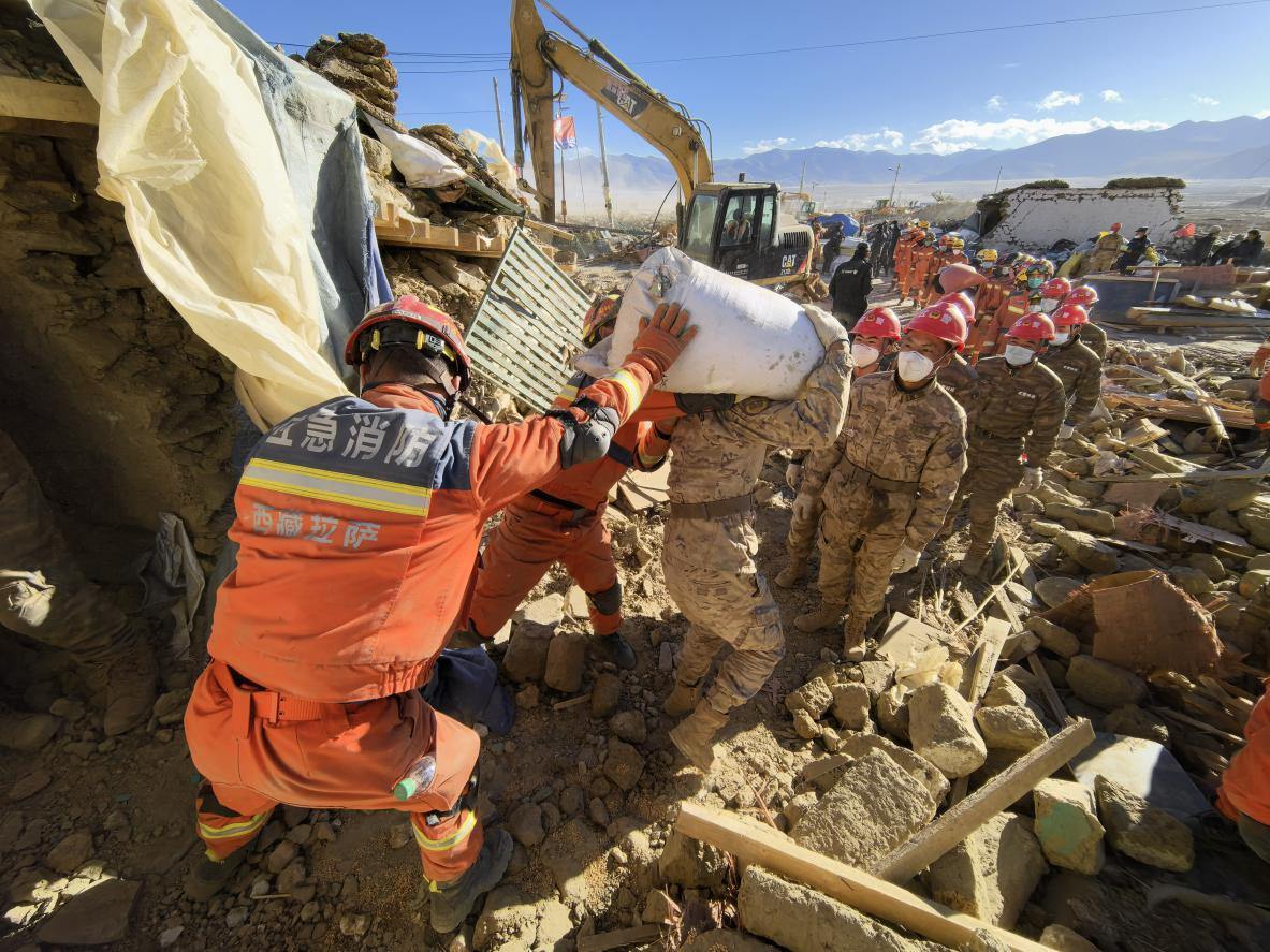 1月11日，定日縣長所鄉(xiāng)古榮村，應(yīng)急消防等救援人員排隊接力搶運掩埋在倒塌房屋下的群眾財物。人民日報記者楊翹楚攝