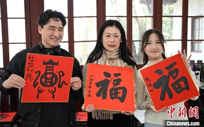 1月20日，外籍留學(xué)生和西泠印社社員李硯(中)展示各自創(chuàng)作的福貼。當(dāng)日，來自巴西、馬來西亞、加納、哈薩克斯坦的外籍留學(xué)生在浙江杭州西泠印社體驗福貼、春聯(lián)和篆刻，感受古老的中國傳統(tǒng)文化。中新社記者 王剛 攝