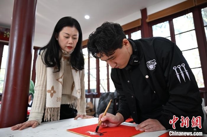 1月20日，外籍留學(xué)生在西泠印社社員李硯指導(dǎo)下寫福。當(dāng)日，來自巴西、馬來西亞、加納、哈薩克斯坦的外籍留學(xué)生在浙江杭州西泠印社體驗福貼、春聯(lián)和篆刻，感受古老的中國傳統(tǒng)文化。中新社記者 王剛 攝