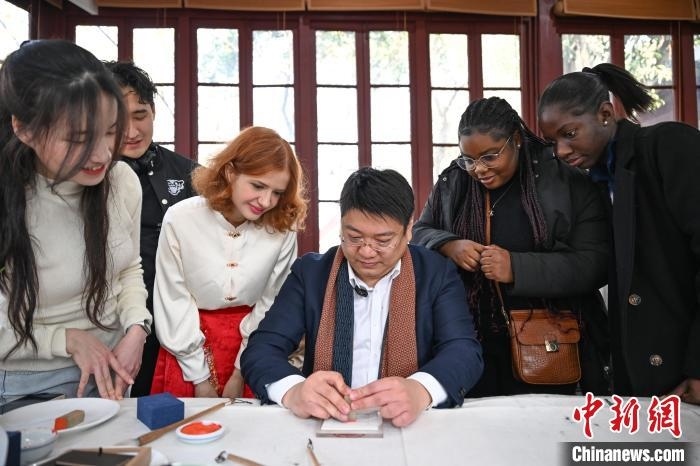 1月20日，篆刻家王臻向外籍留學(xué)生展示篆刻印章。當(dāng)日，來自巴西、馬來西亞、加納、哈薩克斯坦的外籍留學(xué)生在浙江杭州西泠印社體驗福貼、春聯(lián)和篆刻，感受古老的中國傳統(tǒng)文化。中新社記者 王剛 攝