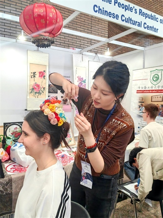 展覽正值羅馬尼亞迎春花節(jié)，國際中文教師志愿者潘婧穎向游客們介紹了國家非物質(zhì)文化遺產(chǎn)——福建泉州的簪花文化。布加勒斯特大學(xué)孔子學(xué)院供圖。