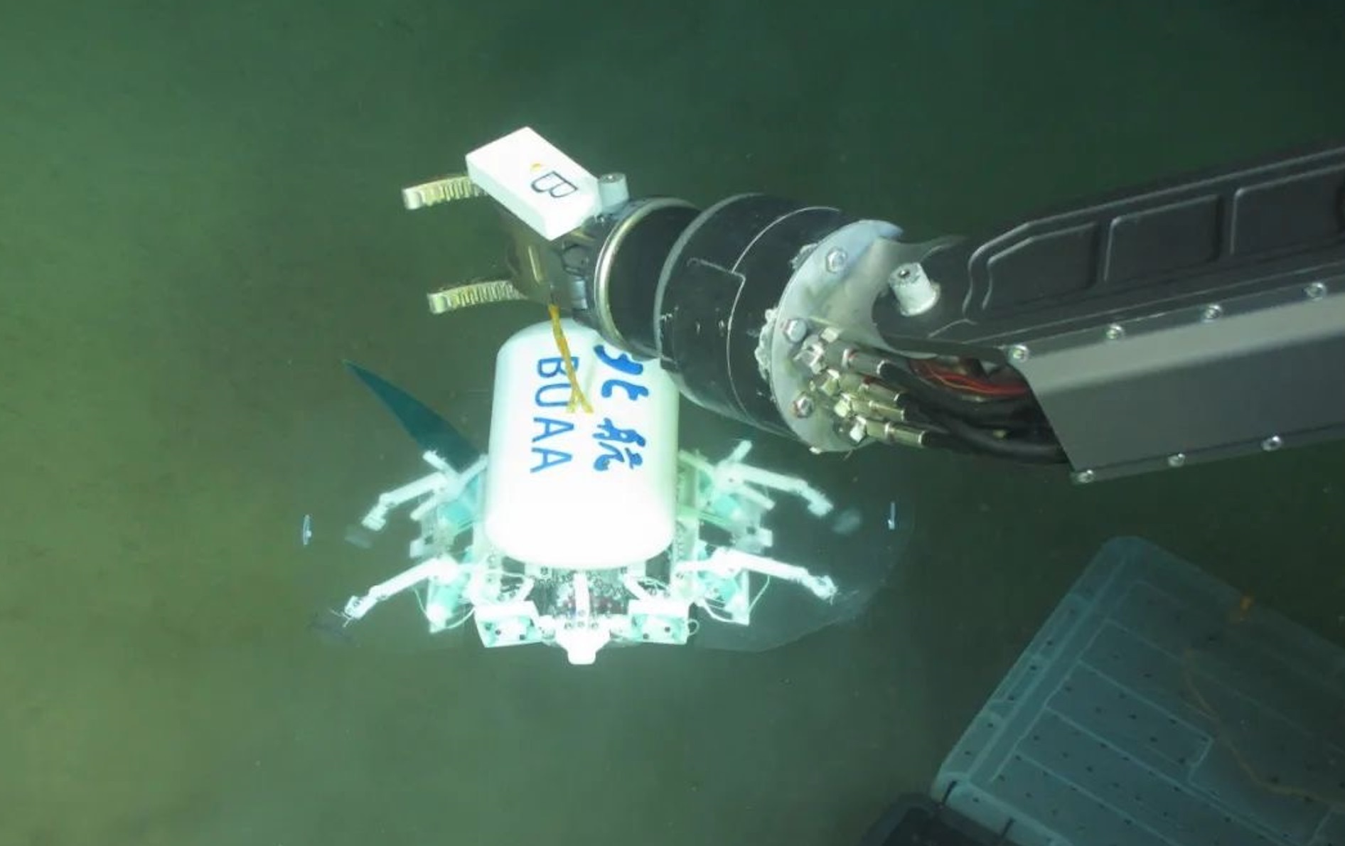 科研人員利用機(jī)械臂將北航深海小型機(jī)器人投于馬里亞納海溝。校方供圖