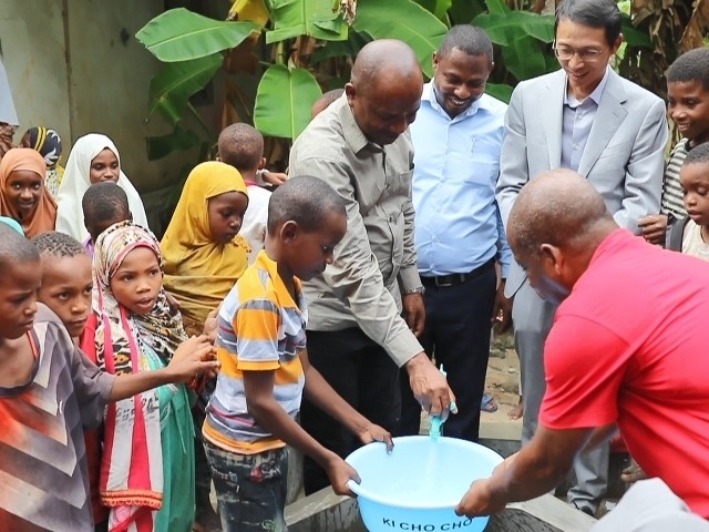 在日前舉行的安全供水工程揭牌儀式上，當?shù)匦∨笥言诠┧c接水。 施亮攝