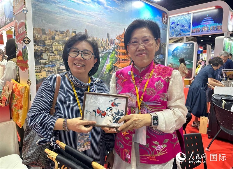 中國“大冶刺繡”傳承人劉小紅（右）參加泰國國際旅游展，向觀眾介紹中國非遺刺繡針法。人民網(wǎng)記者 簡承淵攝