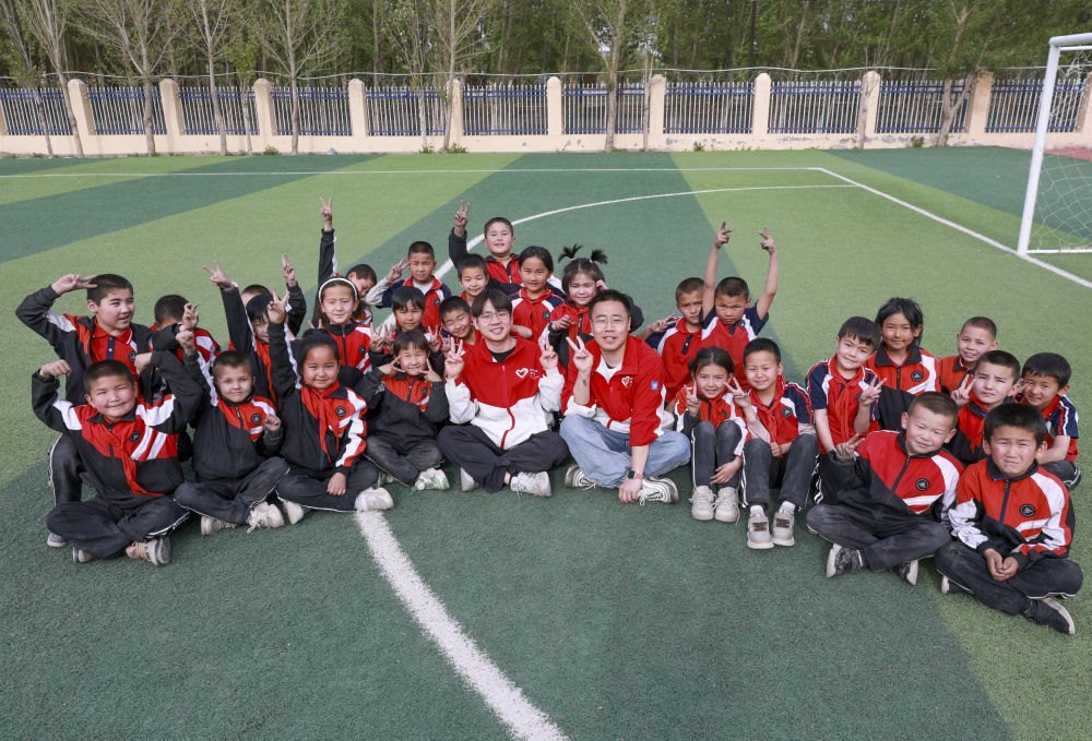 4月23日，在新疆克州阿圖什市哈拉峻鄉(xiāng)謝依特小學(xué)，支教教師王俊文（中左）、李軻凡（中右）和學(xué)生在一起。