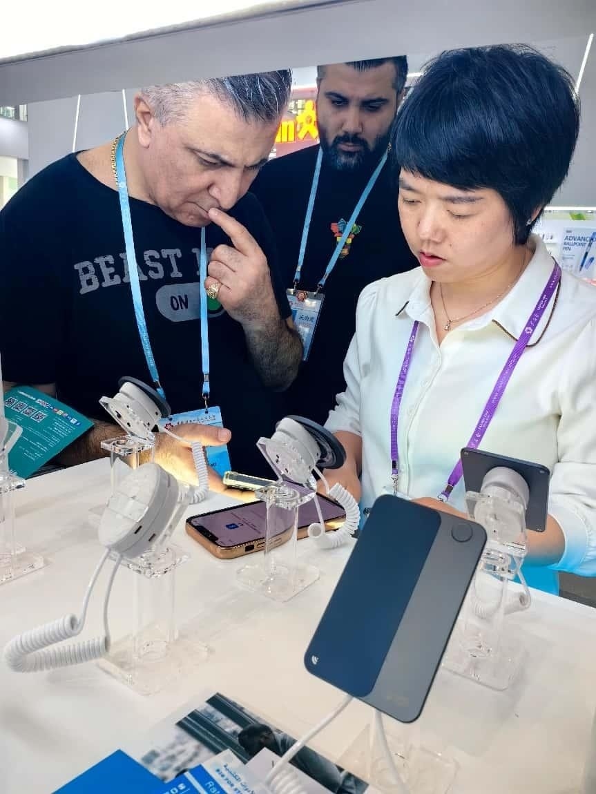 展臺(tái)工作人員向外商展示“AI TOP翻譯終端”。圖片來源：受訪者提供