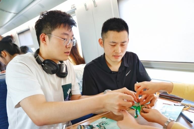 G232次旅客親手制作端午荷包和五彩繩。王磊攝