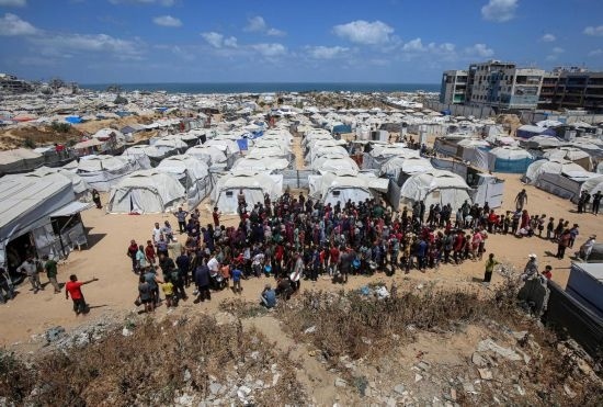 5月28日，人們?cè)诩由吵俏鞑康纳程犭y民營(yíng)等待領(lǐng)取救助食物。新華社發(fā)（里澤克·阿卜杜勒賈瓦德攝）